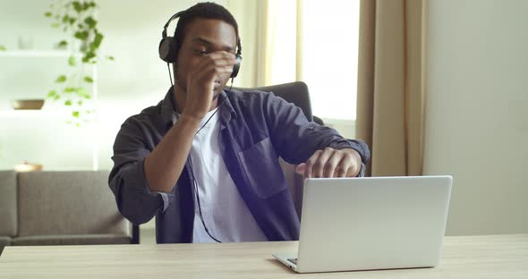 Afro American Man Student Business Person Listening To Music with Headphones Sitting at Table in