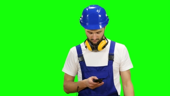 Engineer Dials a Message on His Phone on Green Screen