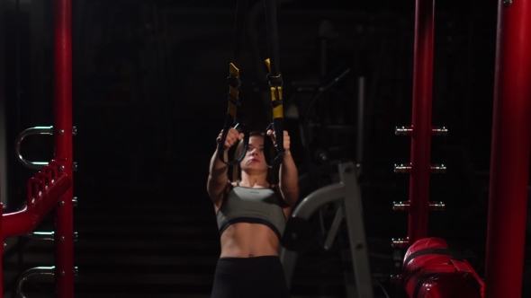 Young Fit Woman Doing Pull-ups on Gymnastic Rings. Muscular Young Female Athlete Exercising with