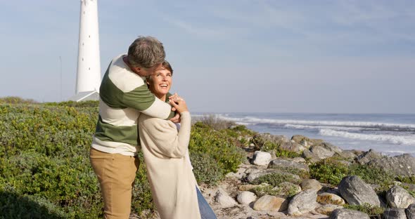 Caucasian couple enjoying free time by sea on sunny day embracing