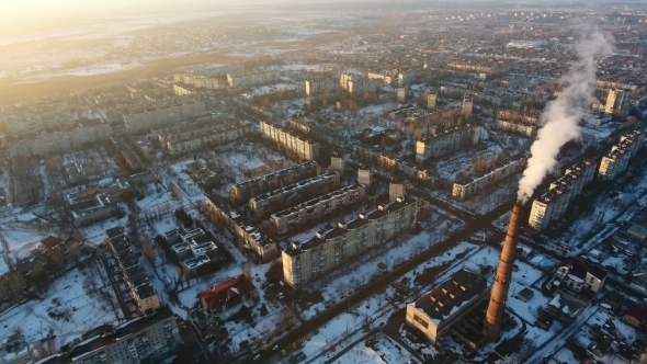 Aerial Shot of High Boiler Chimney with Dense Smoke in European City at Sunset