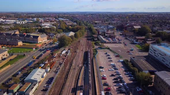 Drone shot of a train leaving Sittingbourne station, flying forwards and panning up.