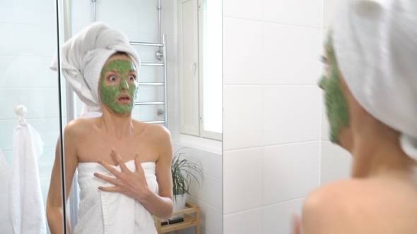 A Woman with a Green Moisturizing Mask on Her Face Suddenly Sees Herself in the Mirror and Is