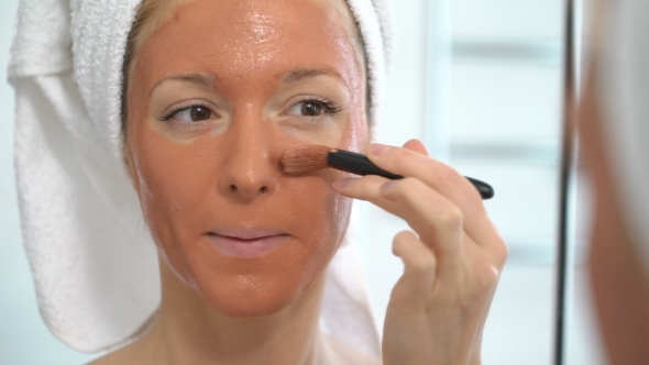 a Young Woman with a White Towel Put on Her Face a Brown Moisturizing Mask