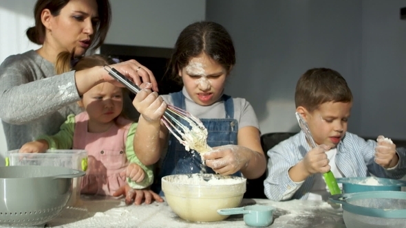 A Beautiful Mother with Three Cheerful Children of Different Ages Kneads the Dough