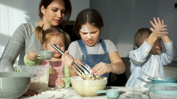 A Beautiful Mother with Three Cheerful Children of Different Ages Kneads the Dough