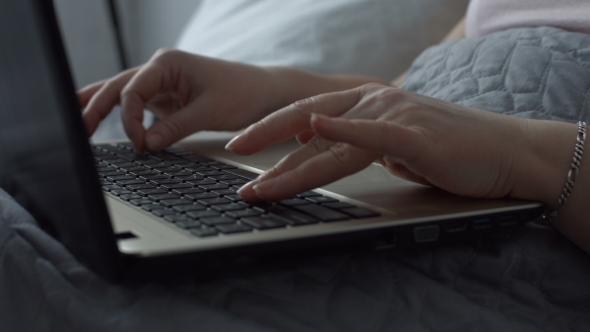 Female Hands Typing on Laptop Keyboard in the Bed