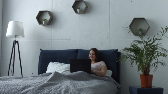 Woman Working on Laptop While Relaxing in Bed