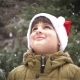 a Child in a Santa Claus Hat Rejoices in the Falling Snow - VideoHive Item for Sale