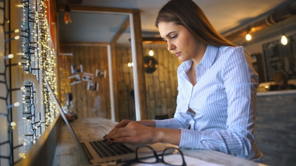 Beautiful Young Woman's Hands Busy Working on Her Laptop Sitting at Wooden Table