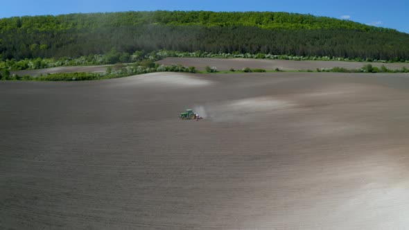 Field with picturesque hills and a moving tractor