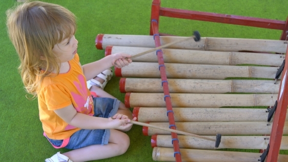 Little Girl Plays with Special Sticks on Traditional Indonesian Instruments
