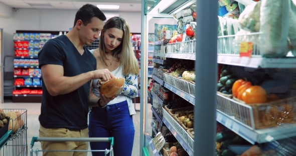 Guy and a Girl Near the Counter of Vegetables and Fruits in the Store / A Couple in a Supermarket