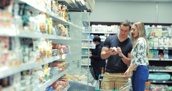 Guy and Girl Choose Products in the Supermarket / Couple in Supermarket / Young Couple Shopping in a