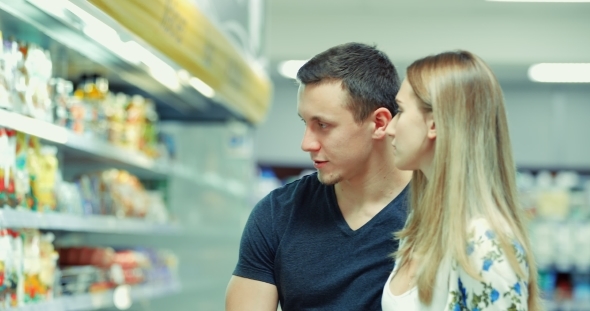 Guy and Girl Choose Products in the Supermarket / Couple in Supermarket / Young Couple Shopping in a