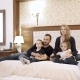 a Happy Family Watching Television in Hotel Room Sitting on Bed - VideoHive Item for Sale