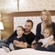 a Happy Family Watching Television in Hotel Room Sitting on Bed - VideoHive Item for Sale