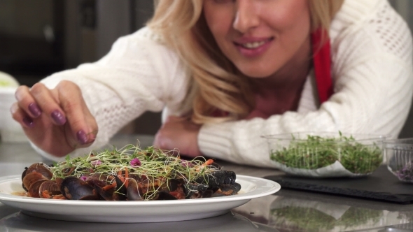Beautiful Woman Decorating Mussels Dish on a Plate Preparing Food at Home