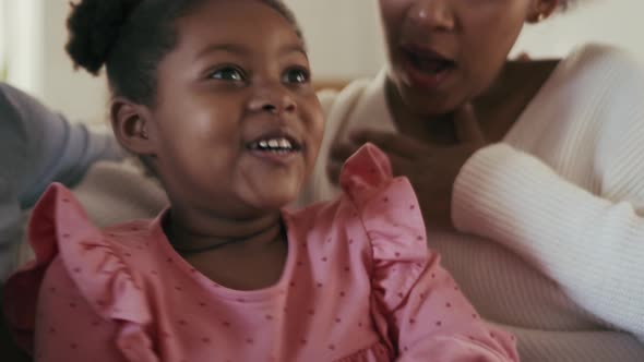 Surprised girl talking with mom and watching TV