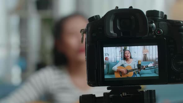 Close Up Of A Camera Monitor Recording Asian Woman Singing And Playing Guitar At Home