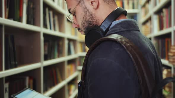 Student using tablet to find book in library alt