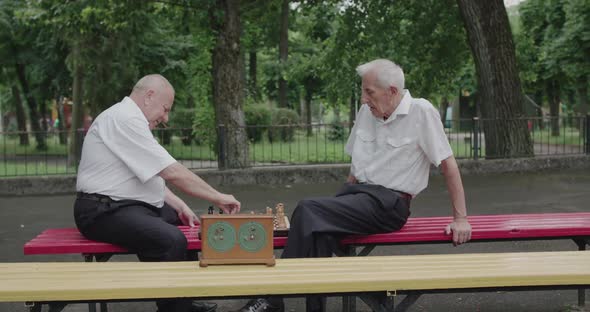 Two Nice Seniors Men Playing the Chess Game Using Clock and Having a Talk