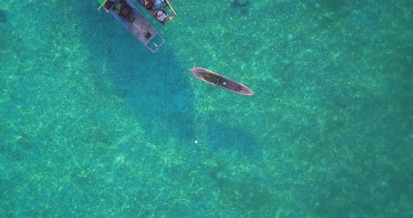 Aerial flight over clear turquoise ocean and locals on boat in Mabul, Malaysia