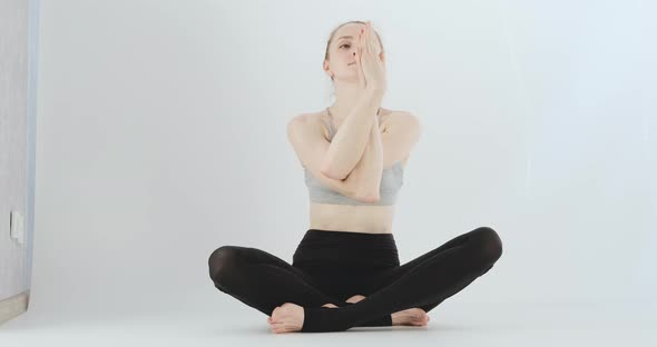 Young Woman Sits in the Lotus Position and Does Breathing Exercises