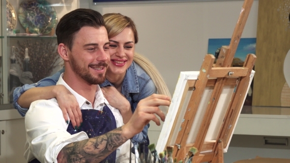Handsome Artist Drawing at His Studio While His Wife Hugging Him
