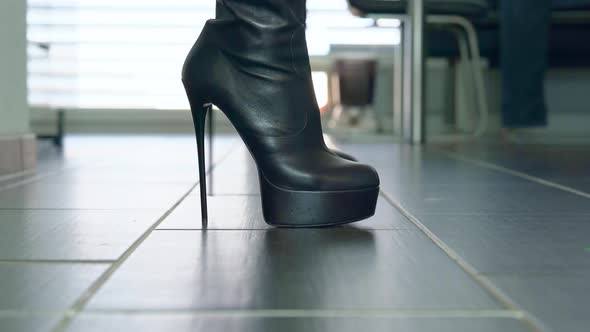 Girl struts in front of the camera in black faux leather high heels block heel boots around