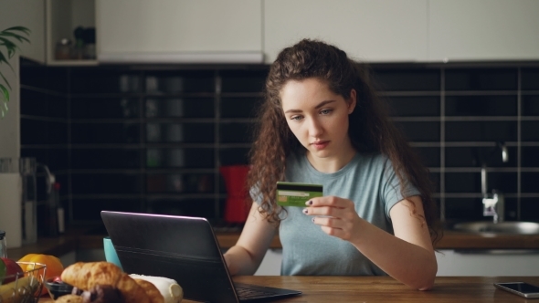 Cheerful Young Woman Having Online Shopping Using Laptop Computer and Credit Card While Have