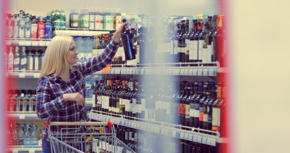 Woman Chooses Wine in the Supermarket Alcohol on Sale