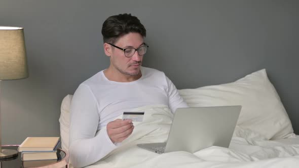 Middle Aged Man Online Shopping Success on Laptop in Bed