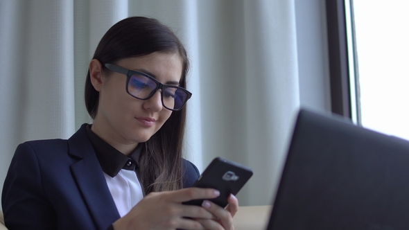 Young Attractive Woman in the Suite Sit with Laptop and Texting.