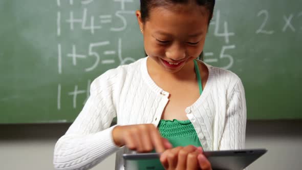 Schoolgirl using digital tablet in classroom at school