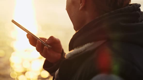 A Man Speaks on the Messenger Against the Backdrop of Sunset