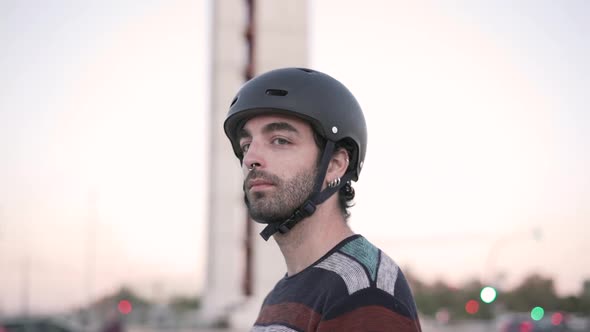 Male skateboarder in helmet standing on city street