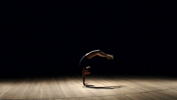 Little Girl Gymnast Doing a Somersault on Stage