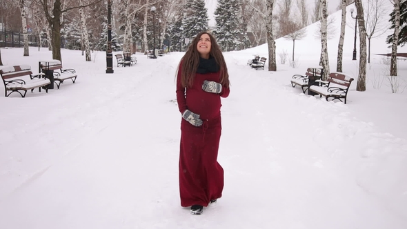 Happy Pregnant Girl Walking in a Snowy Park