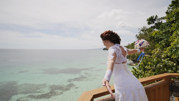 Bride Enjoys Happiness From the Height of the Balcony Overlooking the Ocean and Reefs
