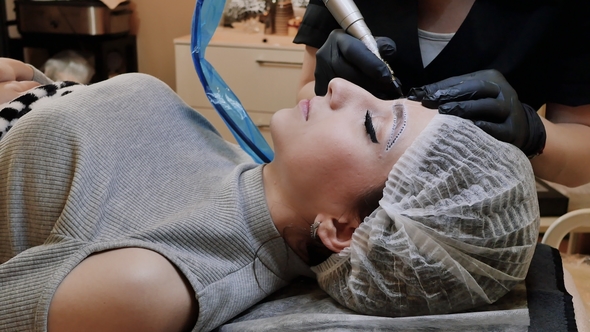 Permanent Tattooing of Eyebrows. Cosmetologist Applying Permanent Make Up
