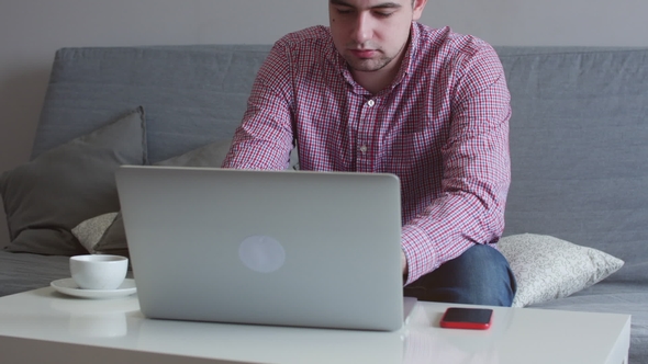 A Person Works From Home Using the Top and Trackpad Young Business Man Sitting at Table Drinking