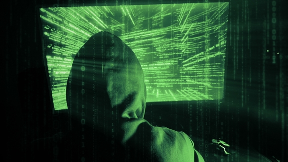 A Man Hacker in a Hood in a Dark Room Works with the Program Code