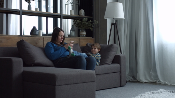 Mom and Kid Relaxing on Couch with Digital Devices