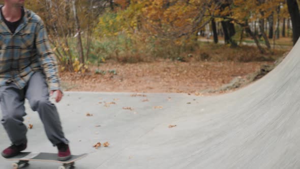 Skater Practicing in the Autumn Concrete Skate Park Making Tricks and Rides in Ramp