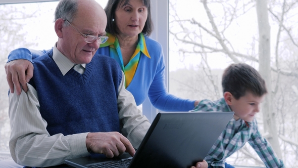 Happy Family, Grandparents with Grandchildren Play on Computer Near Big Window