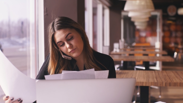 Attractive Businesswoman in Black Shirt Speaking on Phone in Cafe