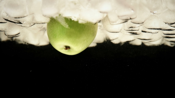 Hand Man Pulls Out a Green Apple From the Water with Ice