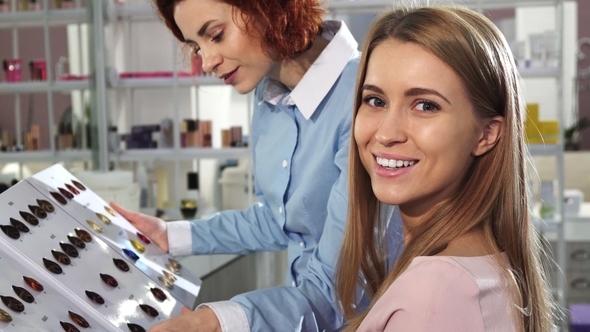 Happy Young Woman Smiling To the Camera Choosing Hair Dye Color with Her Hairdresser