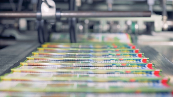 Portions of Coloured Journals Are Getting Collected From a Conveyor Belt By a Person